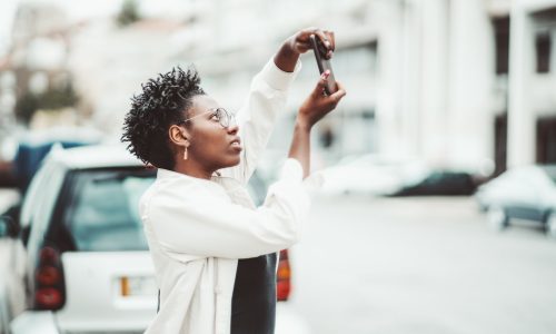 Afro girl photographing on cellphone